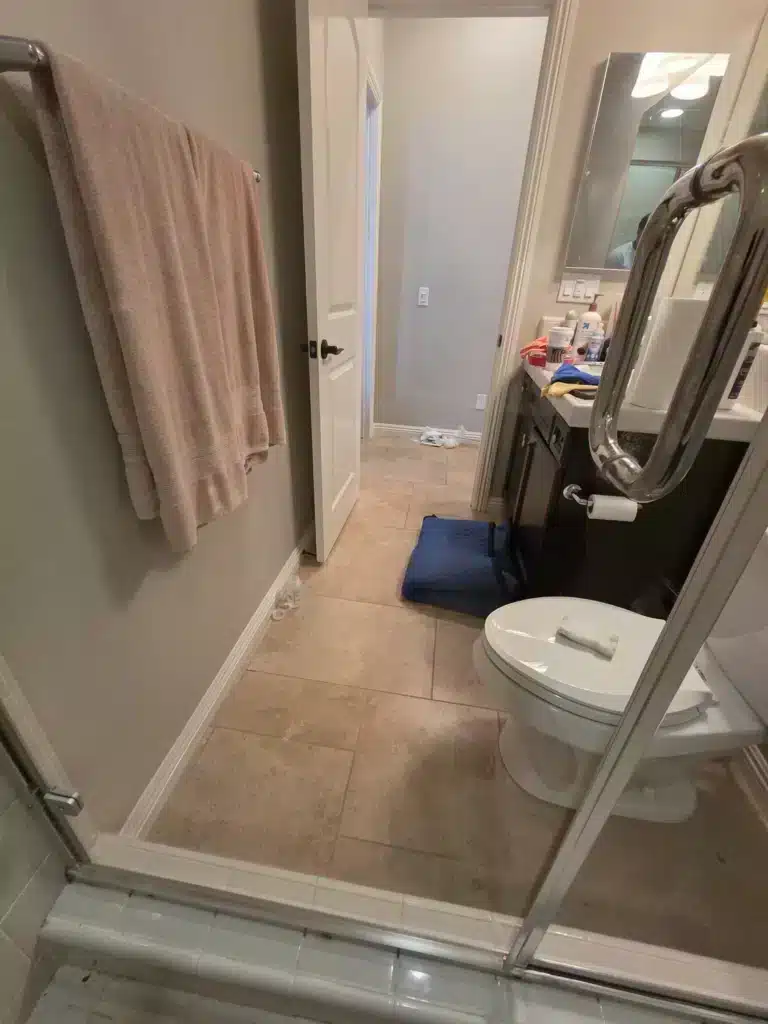 The same framed shower door after restoration, with the towel bar, doorway and vanity clearly visible through the glass